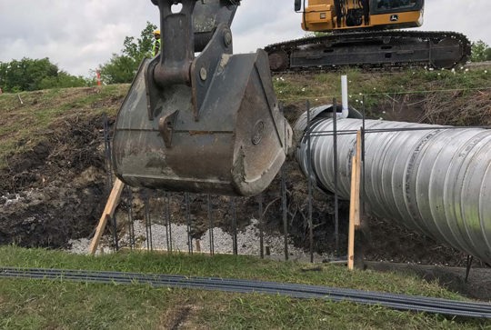 Relining a culvert with corrugated metal pipe. 