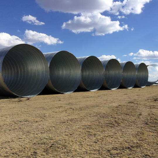 Large diameter corrugated metal drainage pipe staged for installation. 