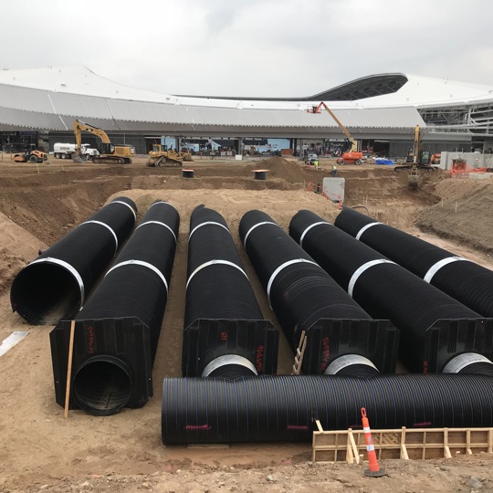A DuroMaxx rainwater harvesting cistern is under construction outside a stadium. 