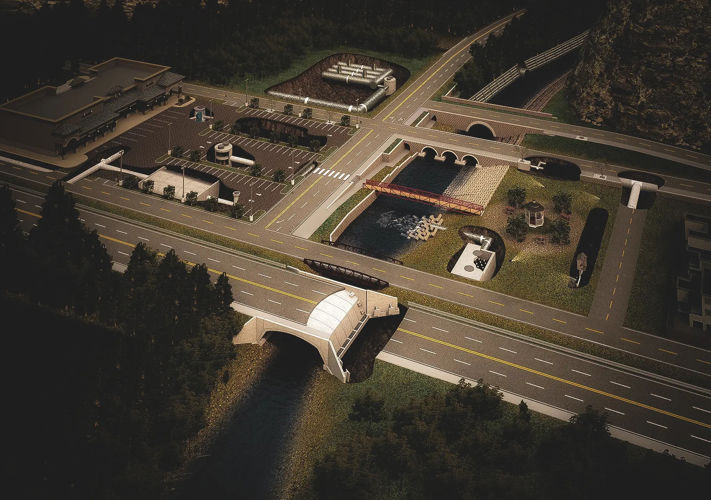 Aerial view of a small town model at night showing roads, bridges, parking lots, and a river running through.